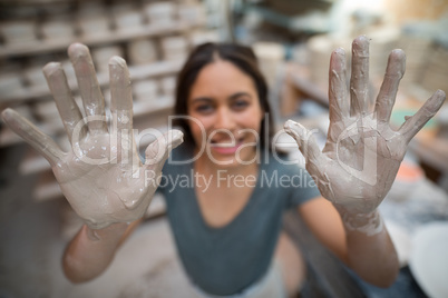Portrait of female potter showing her hands with clay