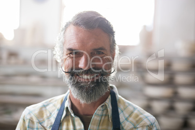 Happy male potter standing in pottery workshop Happy male potter standing in pottery workshop