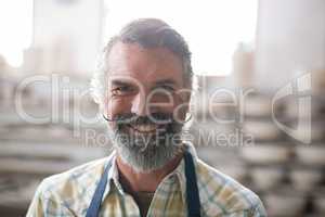 Happy male potter standing in pottery workshop