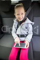 Teenage girl using digital tablet in the back seat of car