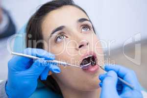 Dentist holding equipments while examining woman at medical clinic