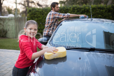 Teenage girl and father washing a car