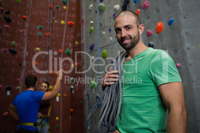 Portrait of trainer standing against athletes interacting in background