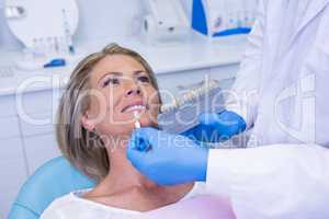 Doctor holding tooth whitening equipment by patient