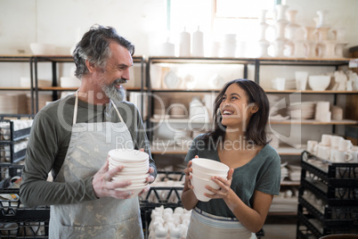 Male and female potter holding ceramic bowls