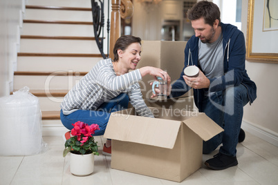 Couple opening cardboard boxes in living room