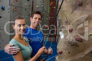 Portrait of smiling athletes holding rope by climbing wall