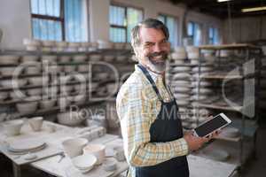 Portrait of male potter using digital tablet