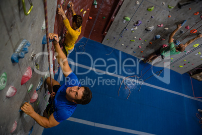 High angle view of confident athletes climbing wall in club