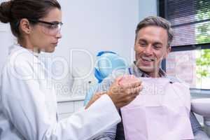 Dentist showing dental mold to man