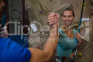 Cheerful athletes giving high five by climbing wall in studio