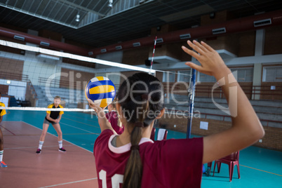 Female players playing volleyball in the court