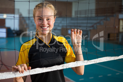 Smiling volleyball female players standing behind the net