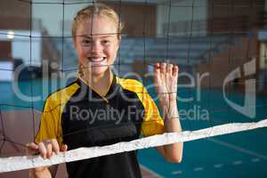 Smiling volleyball female players standing behind the net