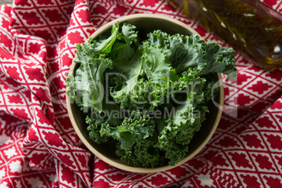Kale leaves with oil bottle and fabric on table