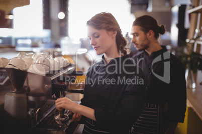 Young wait staff using espresso maker at coffee shop