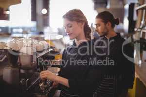 Young wait staff using espresso maker at coffee shop