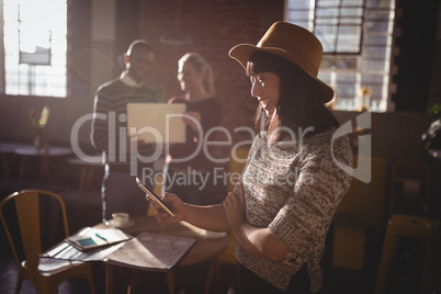 Smiling woman using smartphone against colleauges