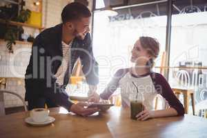 Young man holding tablet computer by woman at coffee shop