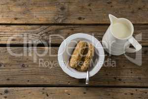 Granola bar and milk on wooden table