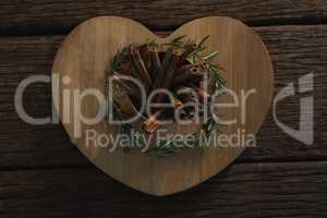 Cinnamon sticks and rosemary on a heart shaped chopping board