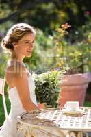 Smiling bride holding bouquet looking away while sitting on chair