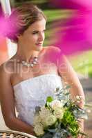 High angle view of thoughtful bride with bouquet sitting in yard