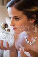 Close up of beautiful bride smelling perfume while sitting on armchair