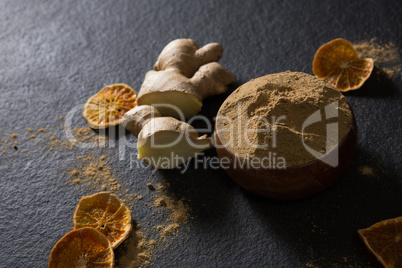 Bowl of ginger powder with ginger and dried lemon