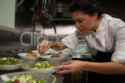Female chef garnishing appetizer plates at order station