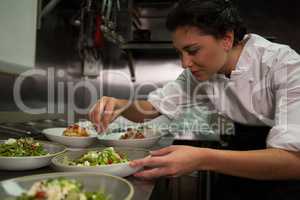 Female chef garnishing appetizer plates at order station