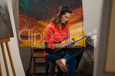 Woman painting in drawing book