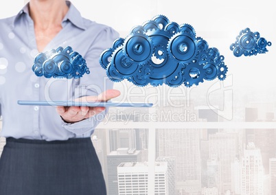 Businesswoman holding tablet with cog gears clouds Businesswoman holding tablet with cog gears clouds