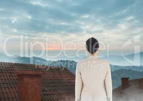Businesswoman standing on Roofs with chimney and misty colorful landscape