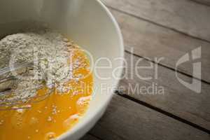 Cropped image of flour on egg yolk in container
