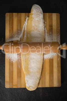 Directly above shot of rolling pin on dough over cutting board