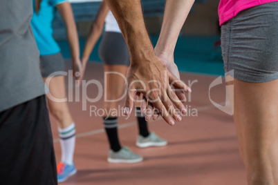 Mid section of volleyball players holding hands