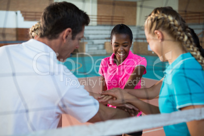 Male coach and basketball players with their hands stacked