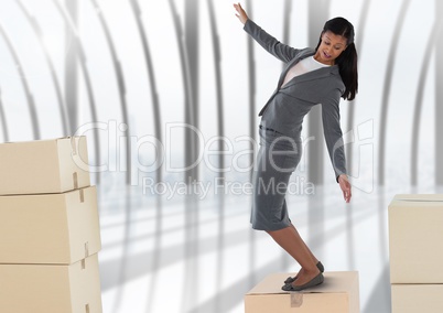 Businesswoman balancing on cardboard boxes by windows