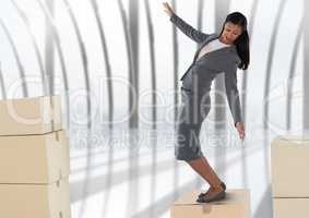 Businesswoman balancing on cardboard boxes by windows