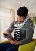 Man in Autumn with tablet and scarf in chair at home