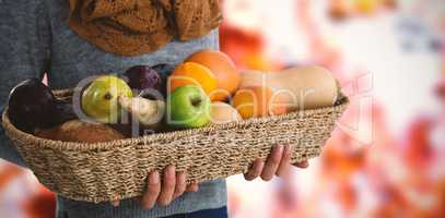 Composite image of mid section of woman holding fruits and vegetables in basket