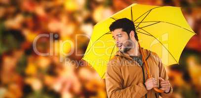 Composite image of young man holding yellow umbrella