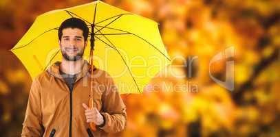 Composite image of portrait of young man holding yellow umbrella