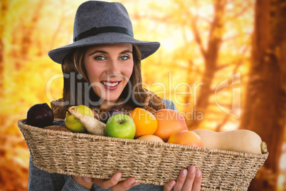 Composite image of portrait of young woman carrying fruits and vegetables in basket