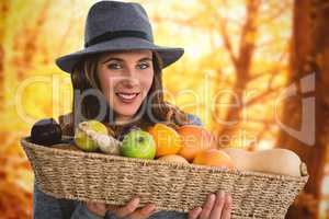 Composite image of portrait of young woman carrying fruits and vegetables in basket