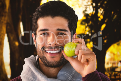 Composite image of close-up portrait of smiling man holding apple