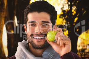 Composite image of close-up portrait of smiling man holding apple