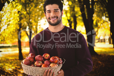 Composite image of portrait of smiling man holding basket with apples