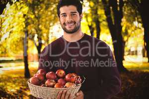 Composite image of portrait of smiling man holding basket with apples